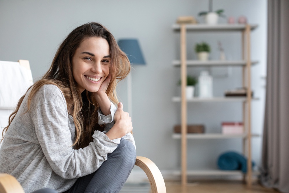 A woman smiling confidently at home, reflecting the positive impact of comprehensive dental care on overall well-being – Dentist in Palos Verdes.