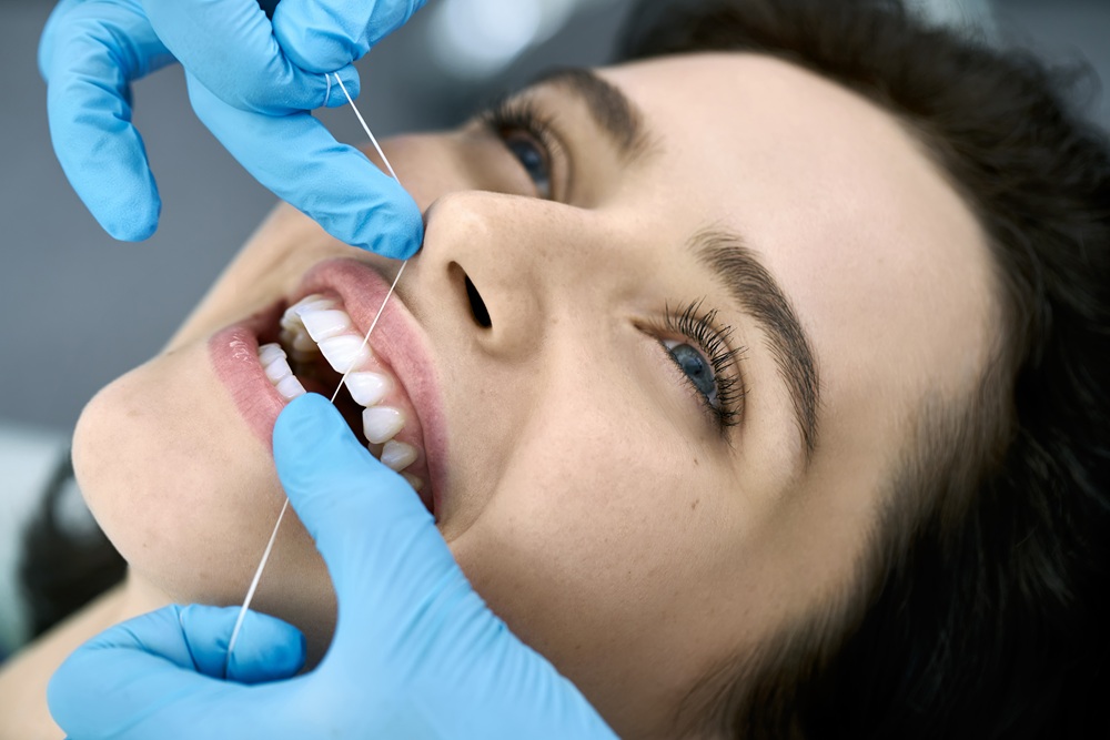 Close-up of a dental professional flossing a patient’s teeth during a routine hygiene visit to remove plaque and promote healthy gums – Redondo Beach Dental Cleanings