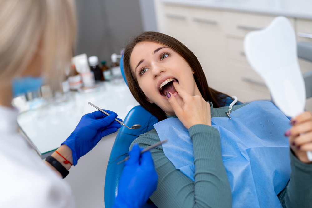 A patient reclines in a dental chair during a professional examination as a hygienist carefully inspects her teeth during a preventive cleaning appointment – Redondo Beach Dental Cleanings