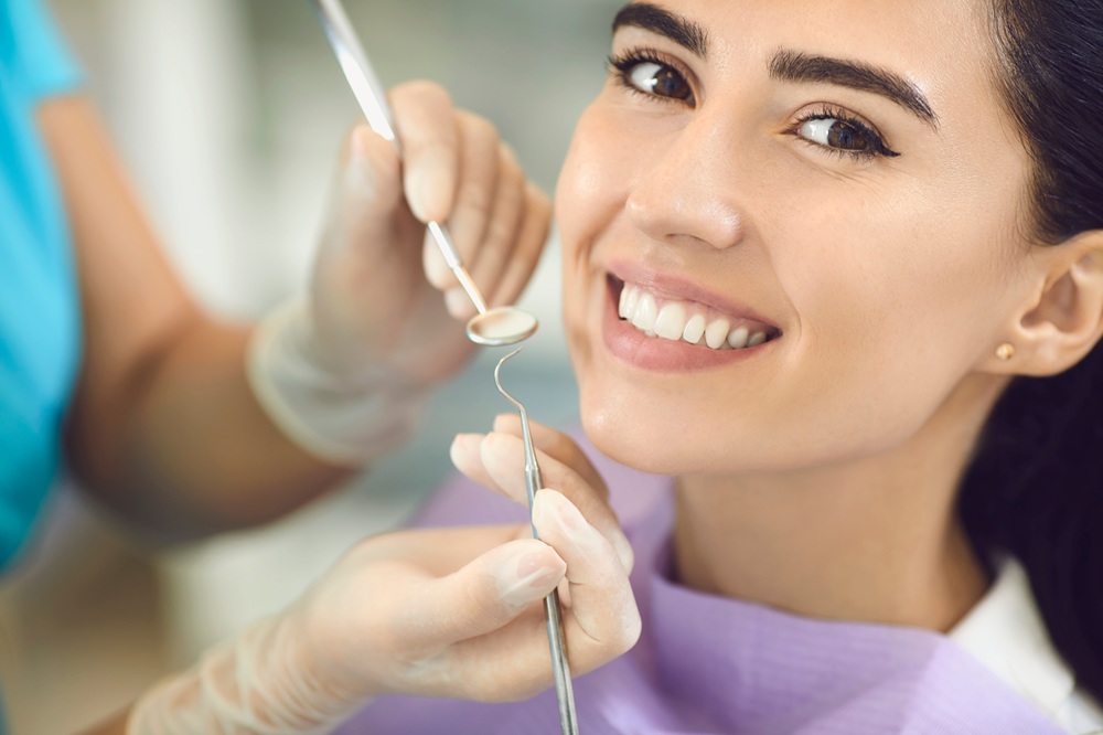 A smiling patient receives a thorough dental examination using a dental mirror and professional instruments to ensure healthy teeth and gums – Redondo Beach Dental Cleanings