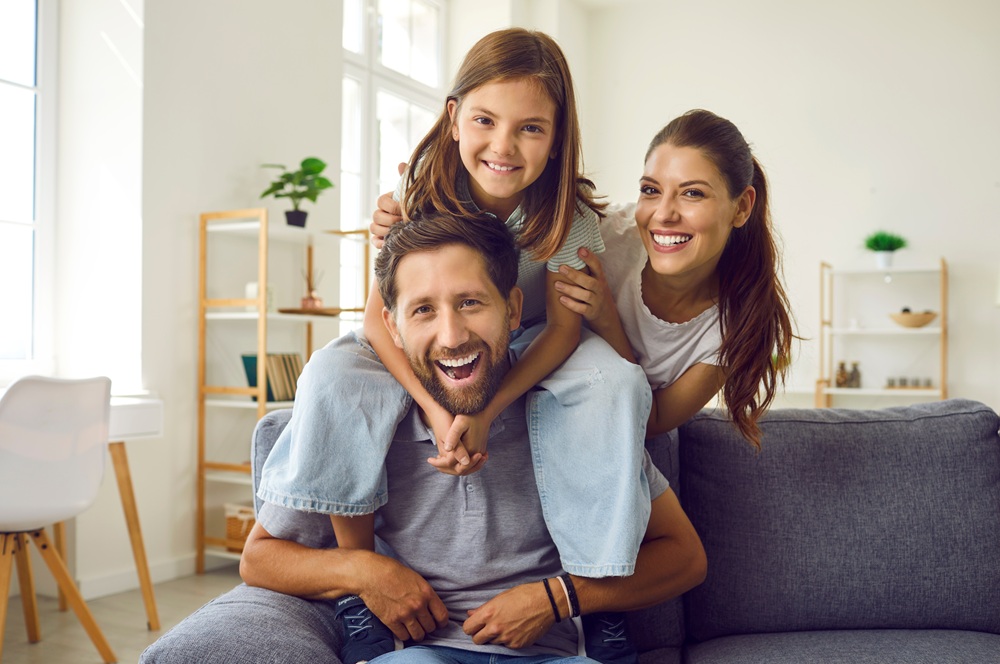A joyful family sharing smiles in a bright living room, representing comprehensive dental care for patients of all ages – Dentist in Torrance CA.