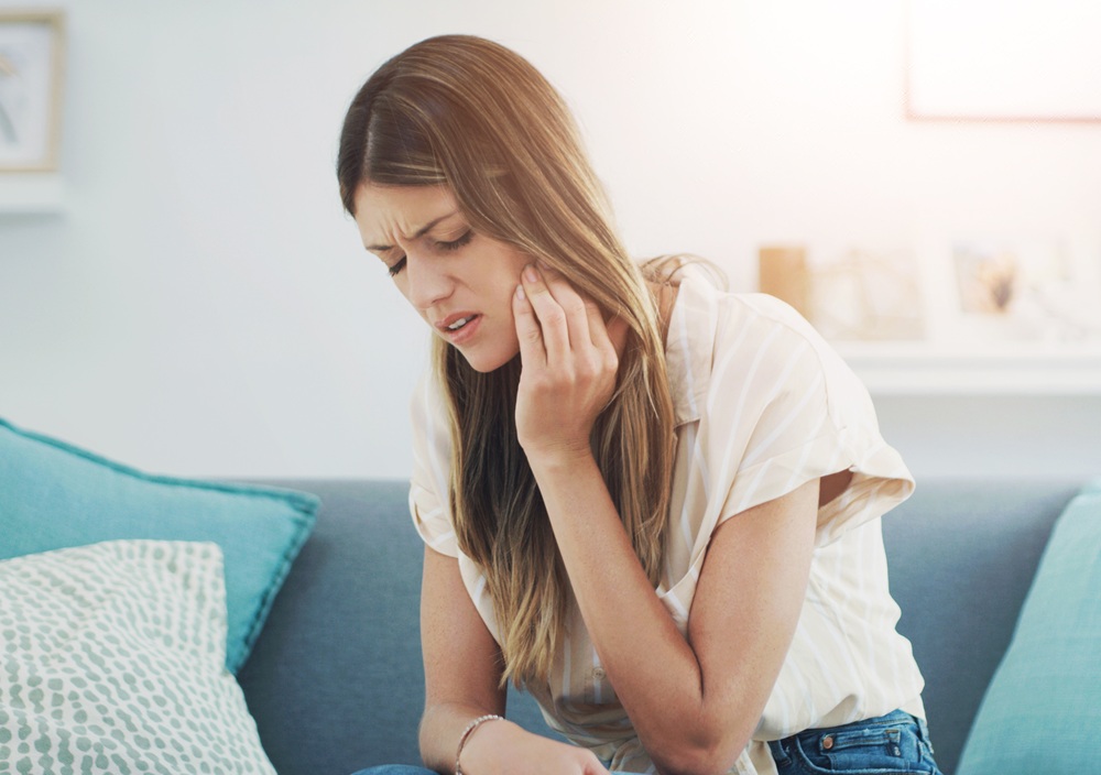 A woman holding her jaw due to tooth discomfort, illustrating the need for prompt evaluation and treatment for dental pain – Dentist in Redondo Beach.