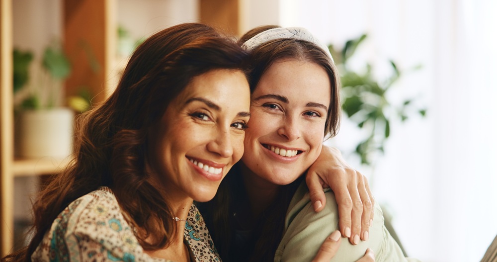 A smiling mother and daughter share a warm embrace at home, highlighting the importance of family dental care and healthy, confident smiles for all ages – Dentist in Redondo Beach.
