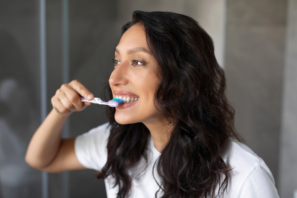 A woman practices daily oral hygiene by brushing her teeth, emphasizing the importance of preventive care for long-term dental health - Dentist in San Pedro CA