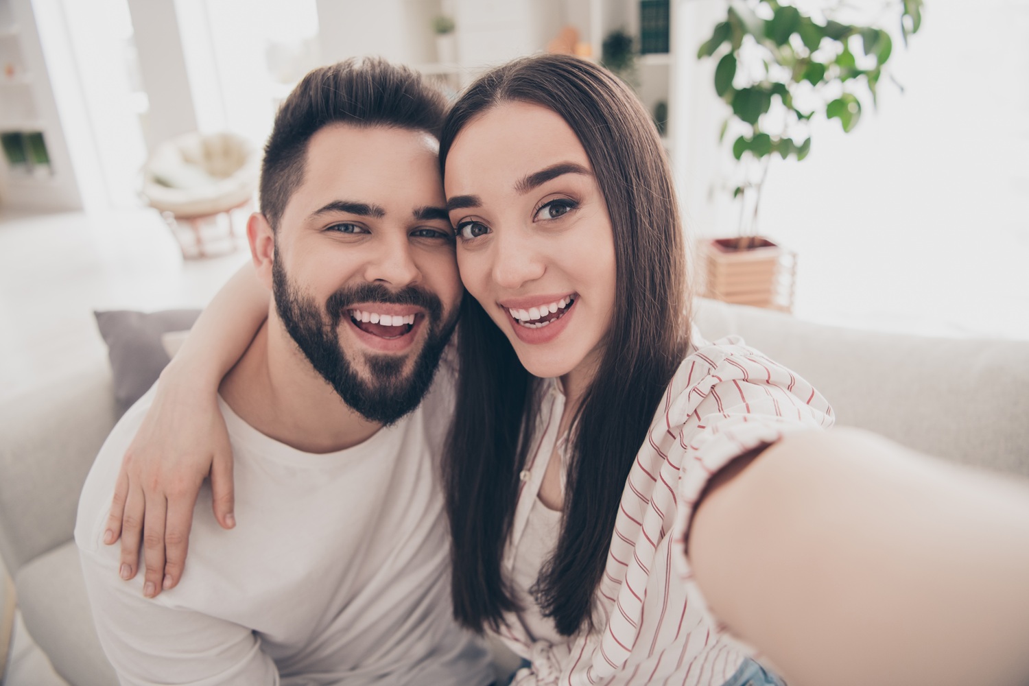 A cheerful couple smiles brightly in a cozy home setting, showcasing healthy, confident smiles supported by professional dental care - Dentist in San Pedro CA