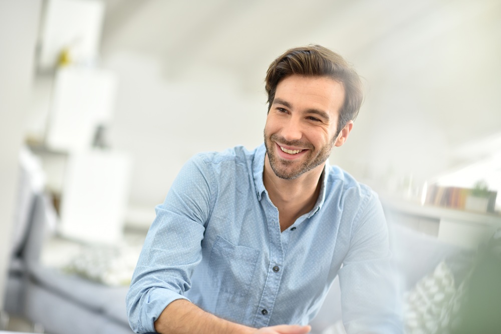 A smiling man in a relaxed home setting, highlighting the benefits of professional dental cleanings and cosmetic dentistry – Dentist in Redondo Beach.