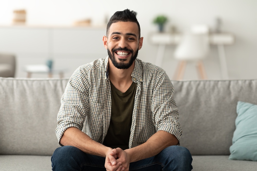 A smiling man sitting comfortably at home, showcasing the results of preventive and restorative dental treatments – Dentist in Torrance CA.