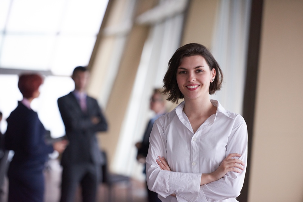 A confident woman smiles in a professional setting, reflecting the confidence that comes from maintaining a healthy, beautiful smile - Dentist in San Pedro CA