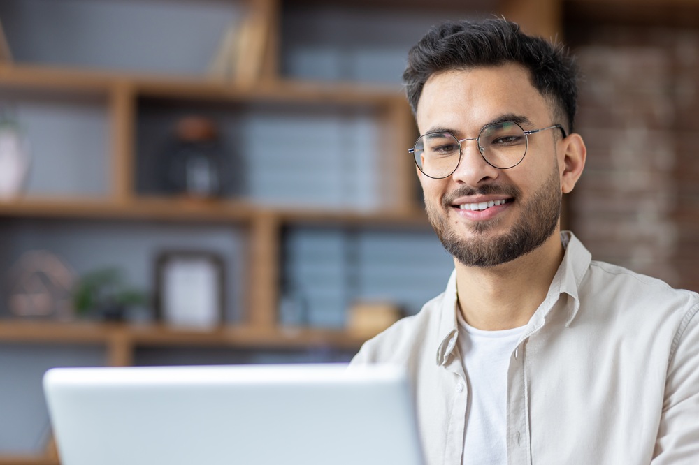 A confident professional smiling while working remotely, representing the lasting confidence of a healthy smile – Dentist in Torrance CA.